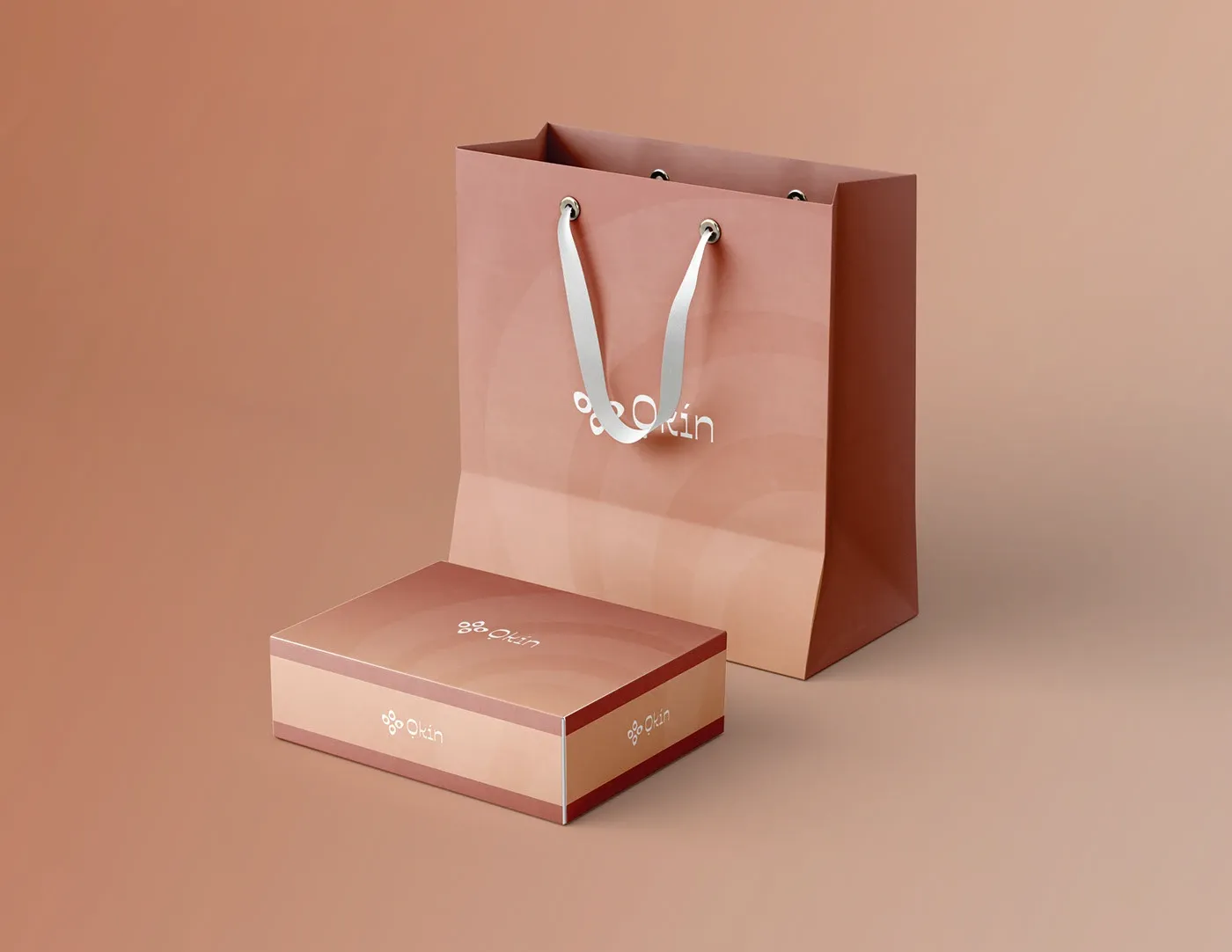 A shopping bag beside a product box in clay pink